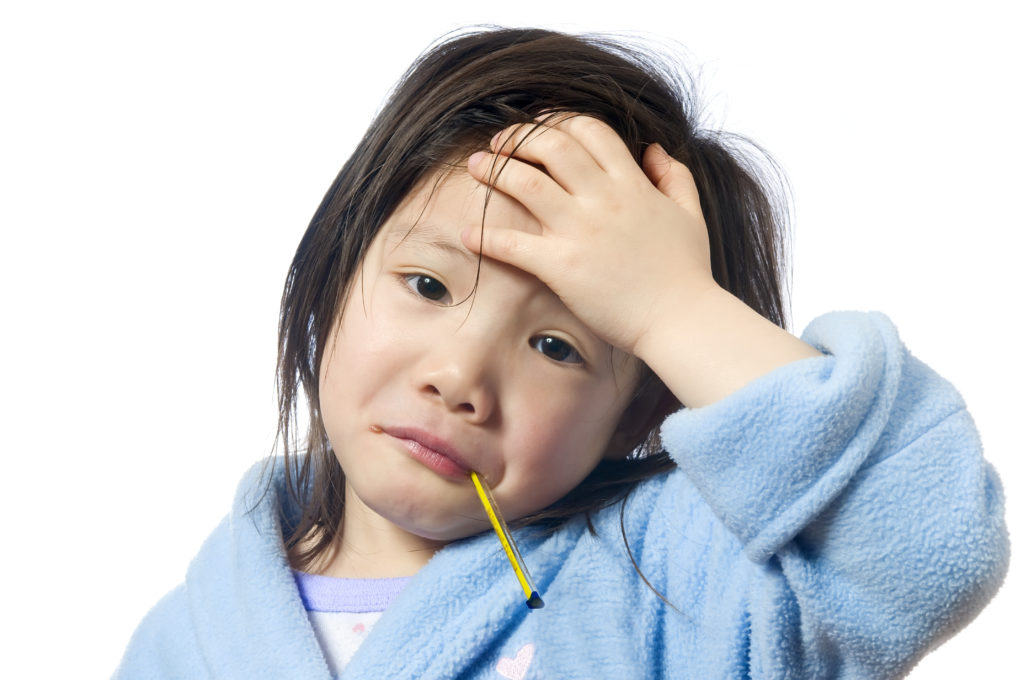 A young girl is sick and having her temperature taken; blog: common childhood illnesses