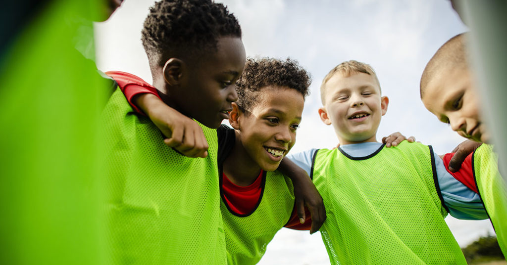 Junior football team huddling together; service page: School, Camp, and Sports Physicals