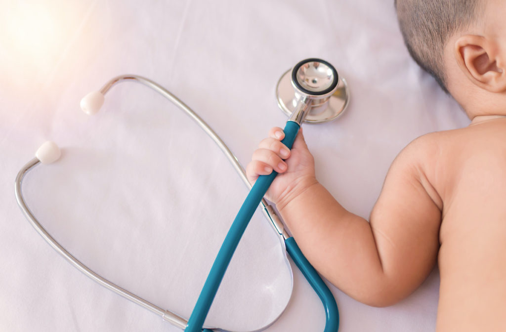 Medical instruments stethoscope in hand of newborn baby girl; blog: Choosing a Pediatrician