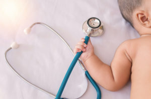 Medical instruments stethoscope in hand of newborn baby girl; blog: Choosing a Pediatrician