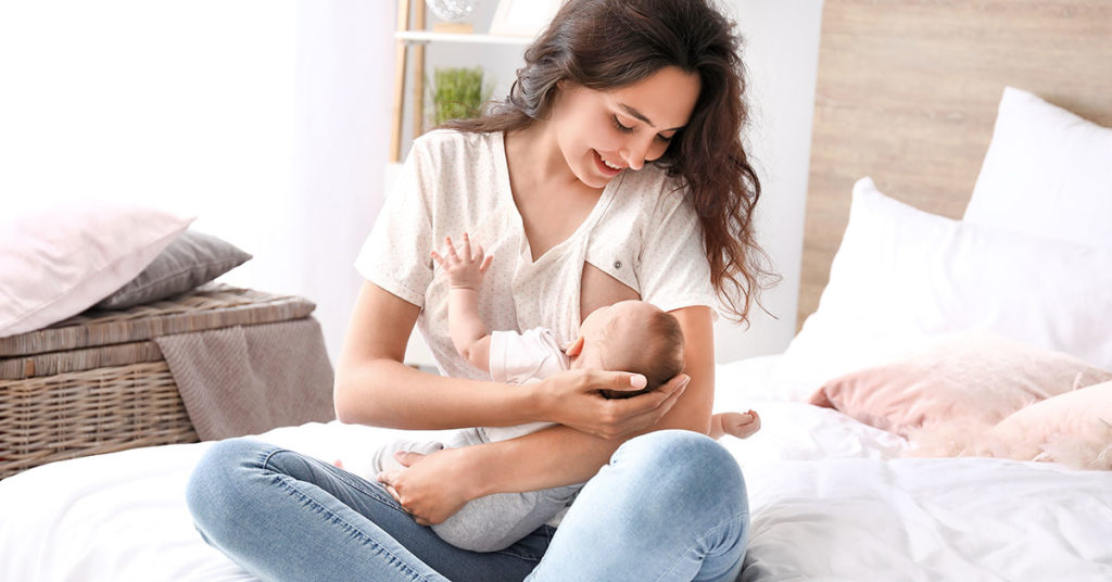 Young woman breastfeeding her baby at home; breastfeeding support provided by wake forest pediatrics